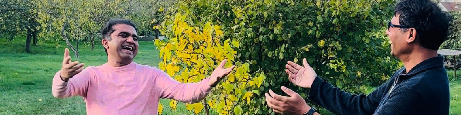 two men reaching out to hug each other in an orchard